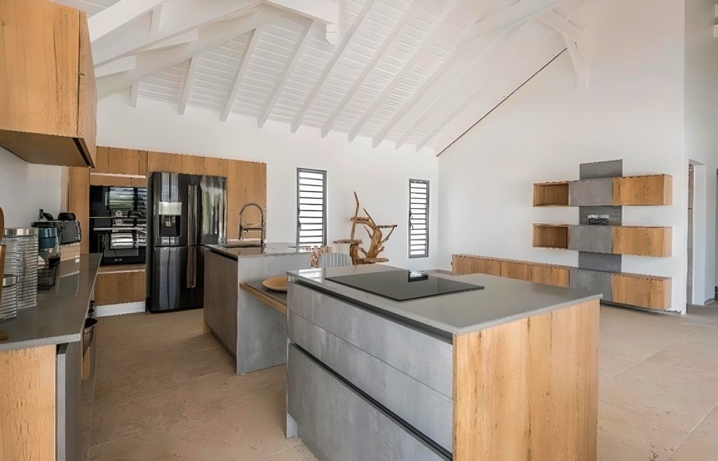 Cuisine sur mesure posée à Baie-Mahault par Artego Cuisines façades noires, plan en pierre sombre et électroménagers intégrés pour un rendu moderne et élégant.