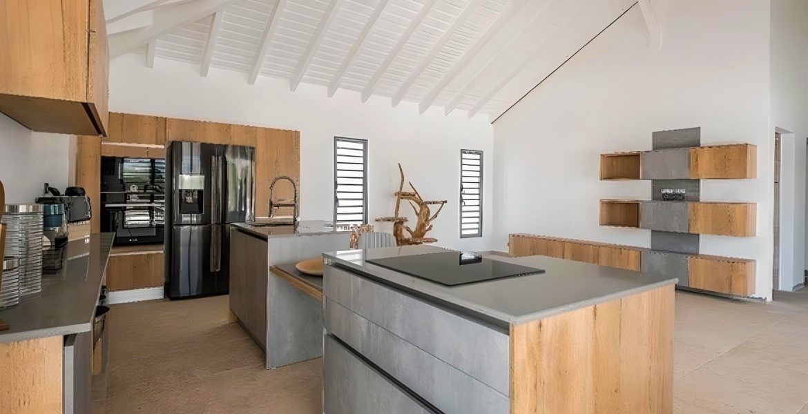 Cuisine sur mesure posée à Baie-Mahault par Artego Cuisines façades noires, plan en pierre sombre et électroménagers intégrés pour un rendu moderne et élégant.