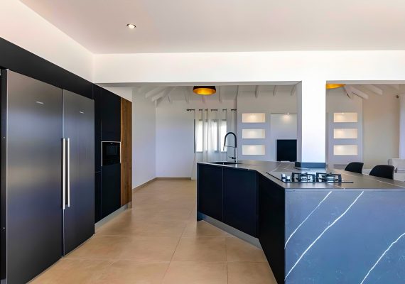 Cuisine sur mesure posée à Baie-Mahault par Artego Cuisines façades noires, plan en pierre sombre et électroménagers intégrés pour un rendu moderne et élégant.